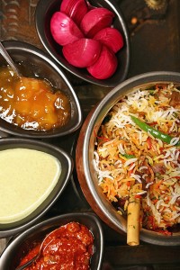 An Indian restaurant dish with condiments, chutneys, sauces, spices, onions
