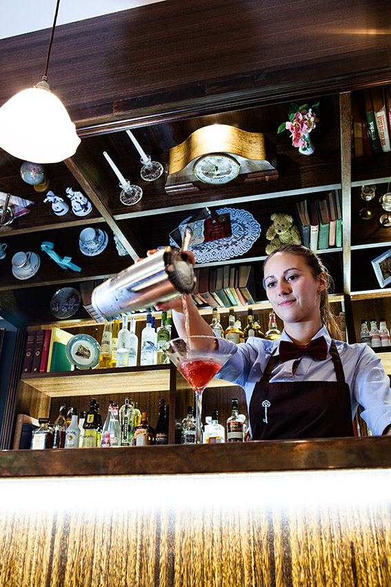 Bartender pouring a cocktail into a Martini glass