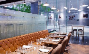 Restaurant table settings with plush leather bench seating and an interior of glass and steel.