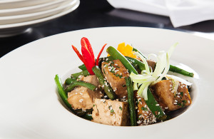 A_fine_dining_vegan_dish_of_tofu_beans_carrots_onion_sesame_seeds_chilli_served_in_a_white_bowl