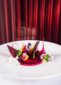 Photo of an elaborately-plated salad served on a white round plate in a fine-dining restaurant